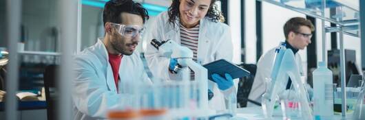 Scientists talking in lab by microscope. 